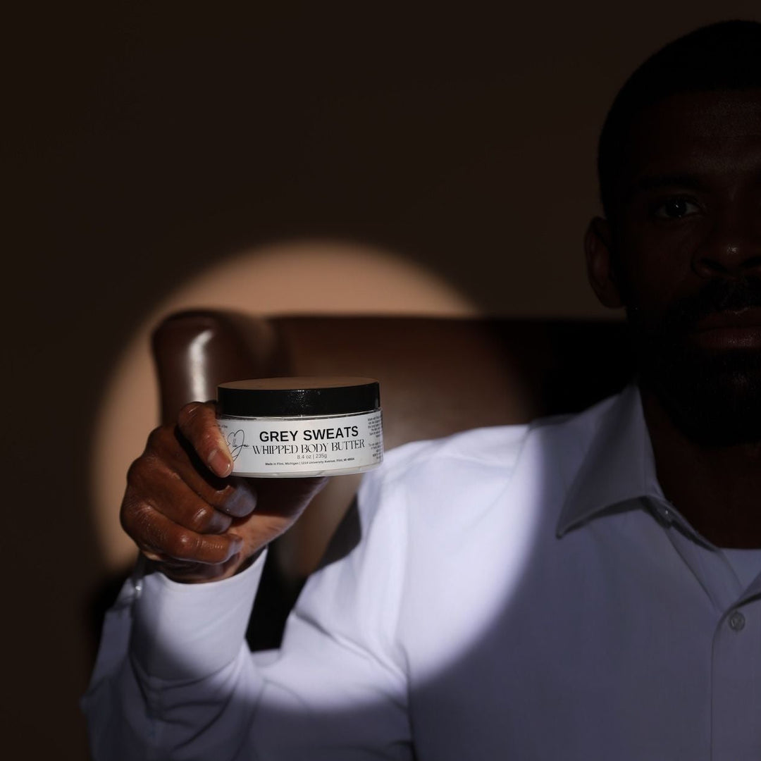 Person holding a jar of 'Grey Sweats' product against a dark background